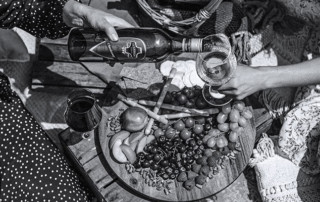 People sharing a bottle of Ivanhoe wine over a picnic of fruit